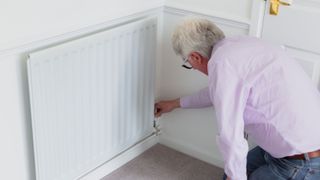 Senior man adjusting heat on radiator