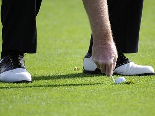 Ball plugged in the fairway, with golfer repairing pitch mark using a tee