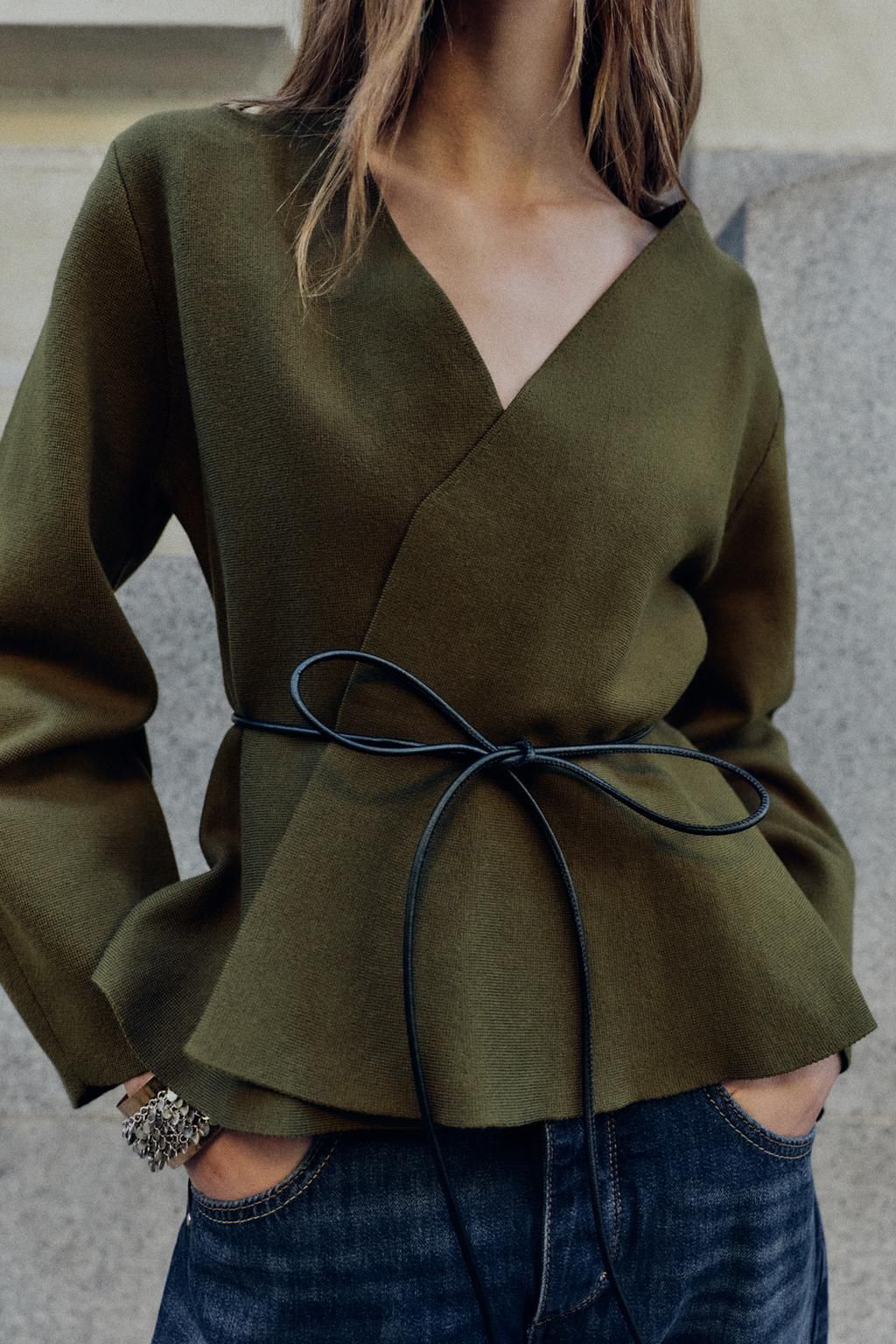 Woman wears green cardigan with belt and blue jeans