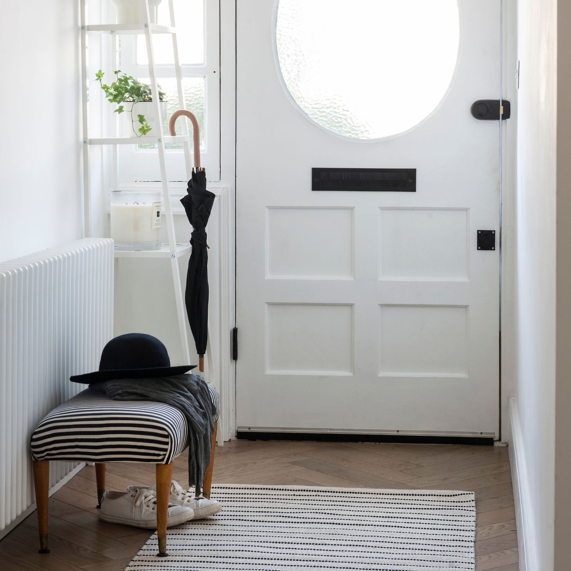 White hallway with a white wooden door and a storage rack and bench