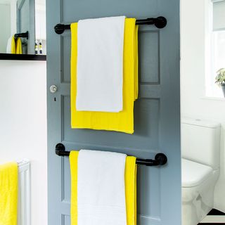 bathroom with grey coloured door and towel rail with towel and bath mat