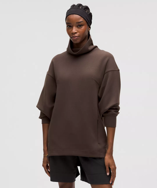 Female model wears brown tunic with high neck