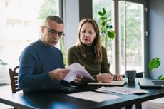 Wife and husband reviewing paper financial statements at home
