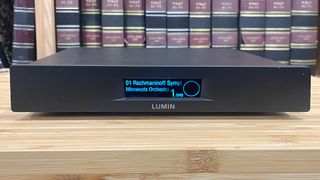 Lumin U2 Mini network streamer on wooden hi-fi rack in front of bookcase with Rachmaninoff on display