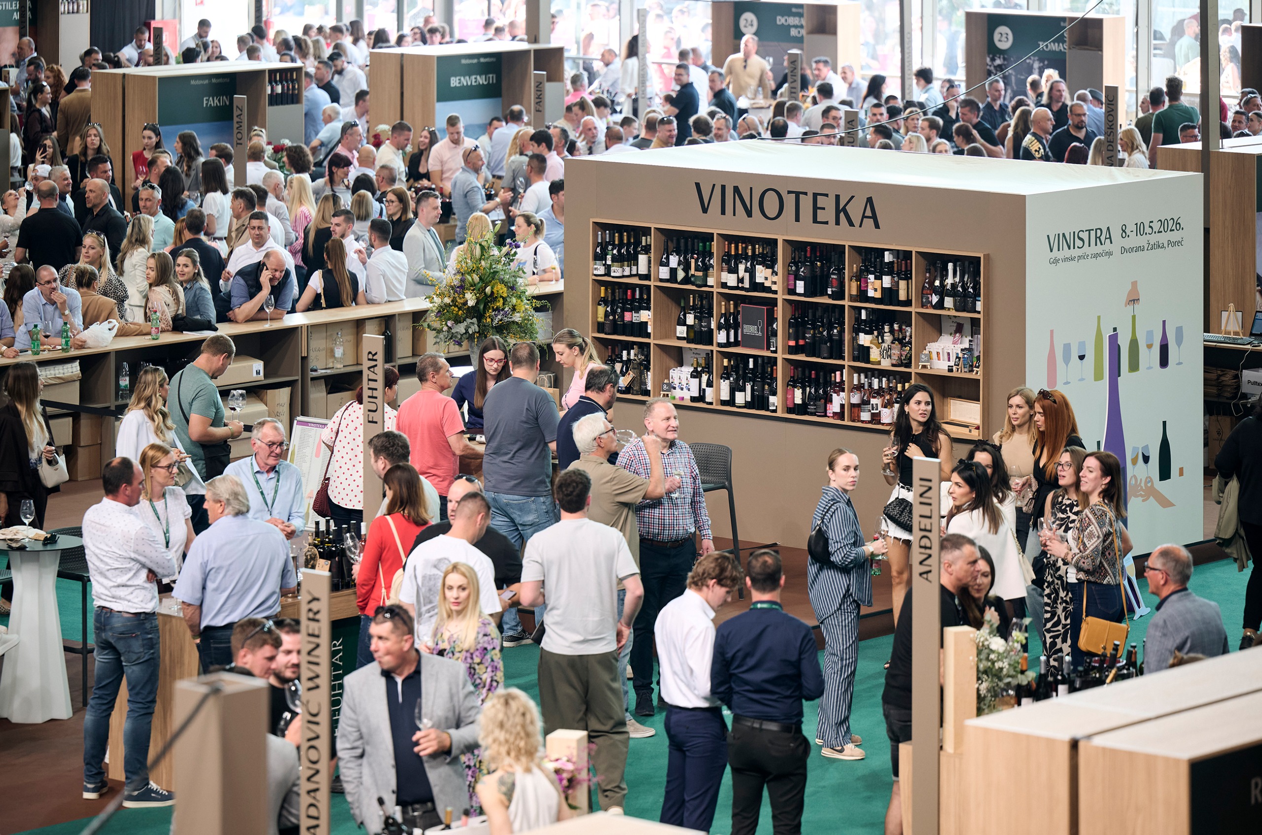 Vinistra 2026 fair, with a stand saying Vinoteka with lots of wines, and people with wine glasses