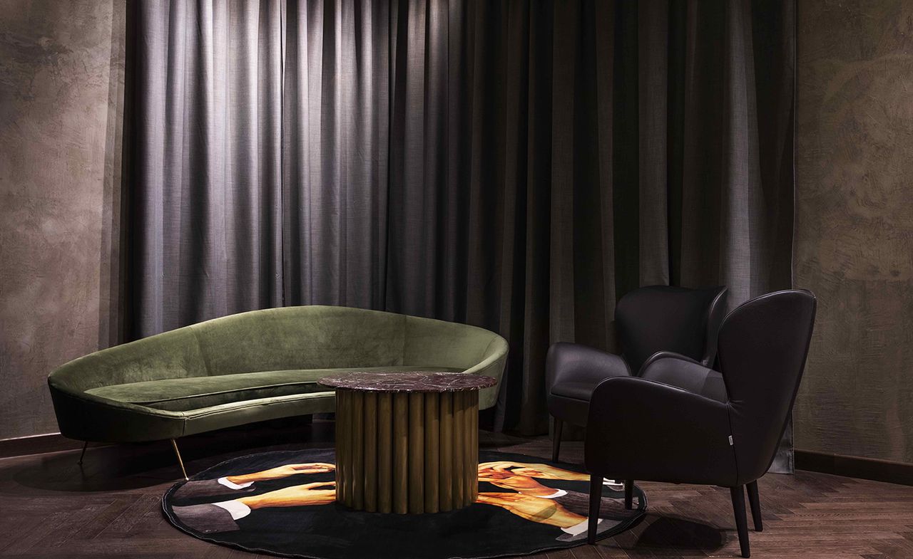 Chapter Roma room with green sofa, black chairs and rug