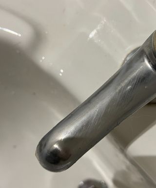 A chrome faucet over a white porcelain sink