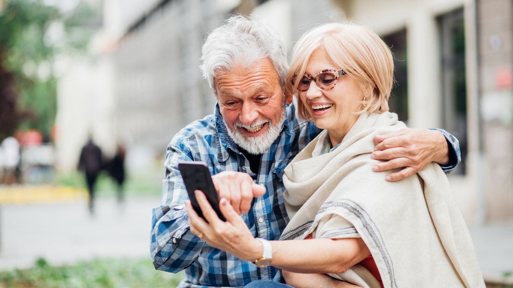 A couple looking at a smartphone smiling, while traveling abroad. 