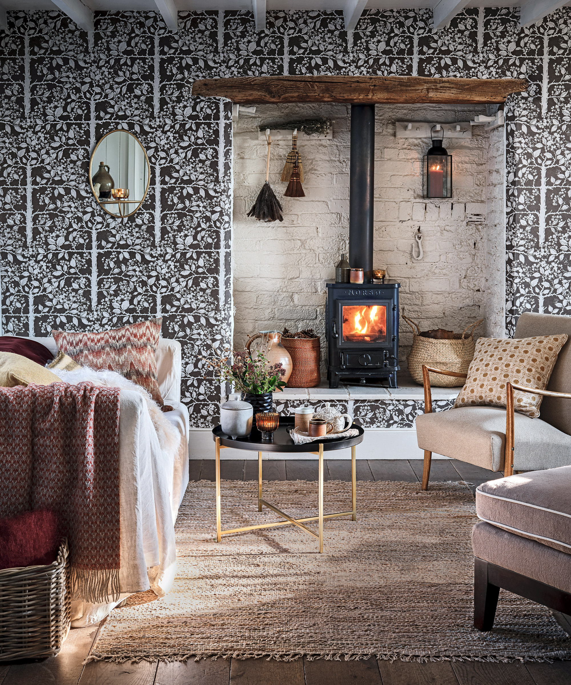 A dark patterned wallpaper, woodburning stove and textured decor illustrate cozy living room ideas.