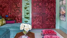 A living room with a blue sofa, teal walls, and imitation red 'jewel' doors