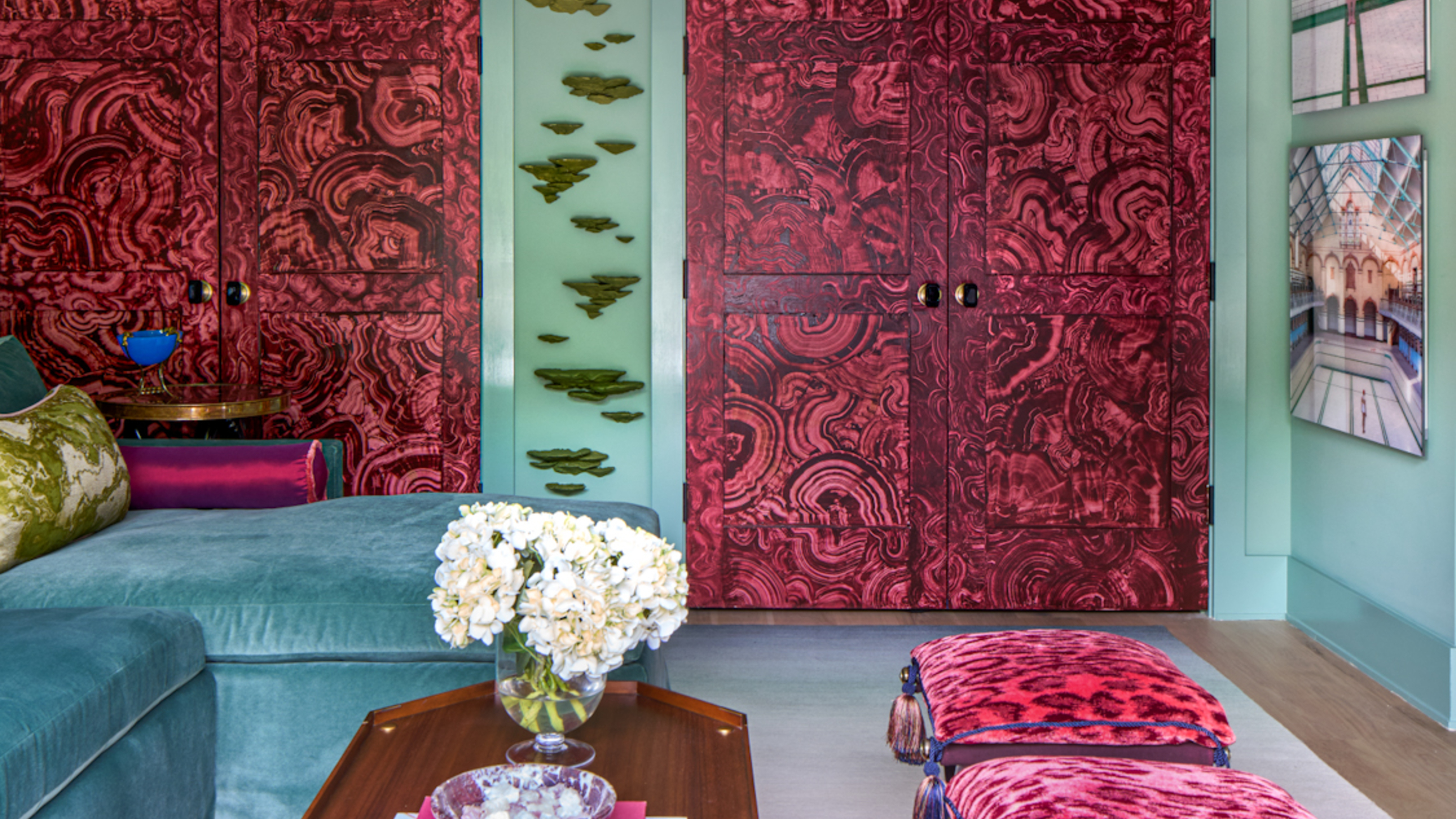 A living room with a blue sofa, teal walls, and imitation red &#039;jewel&#039; doors