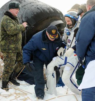 NASA astronaut, Jeffrey Williams, mission commander being helped out of the Soyuz TMA-16 spacecraft after landing on the frozen steppes.