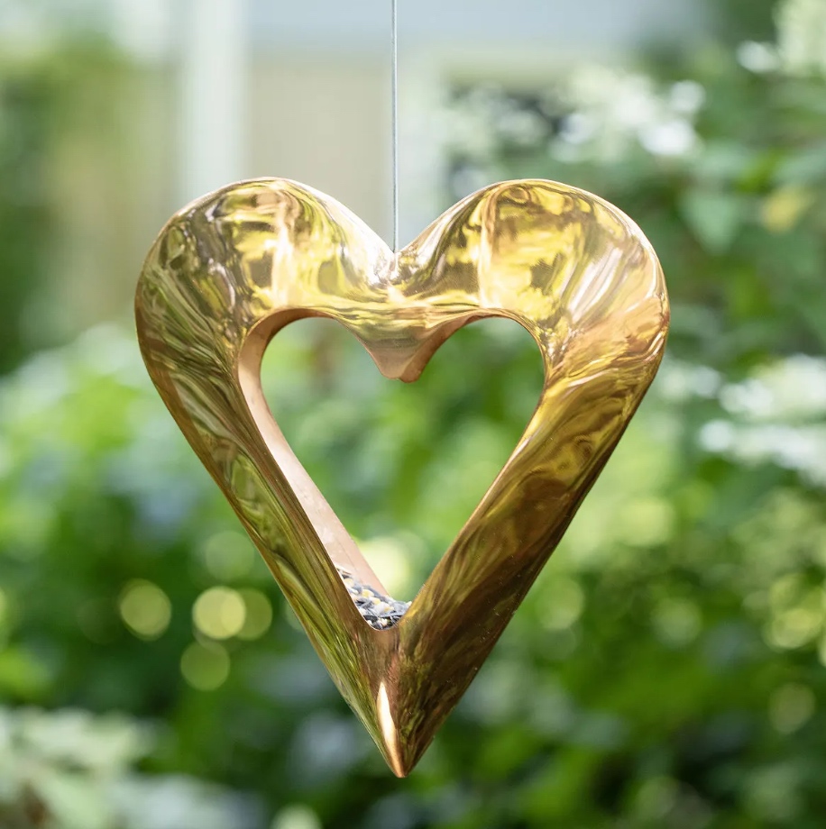 copper heart bird feeder from Uncommon Goods hanging from branch in garden
