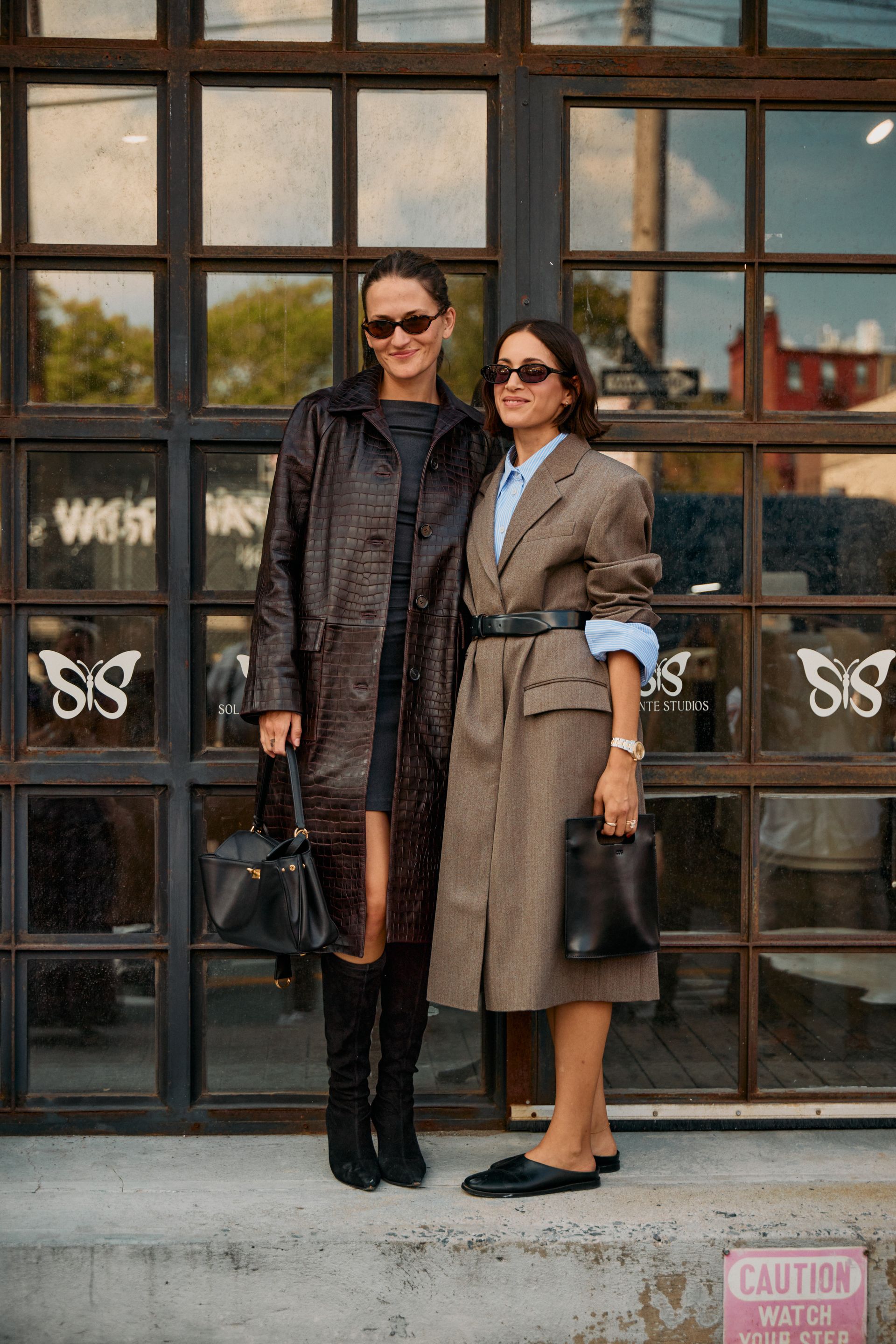 Eliza Huber wearing a croc leather coat at the COS F/W 25 show during NYFW. She's with Cassandra Lanrick, who is wearing a plaid coat.
