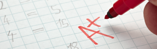 A red pen hovering over an "A+" on a math paper