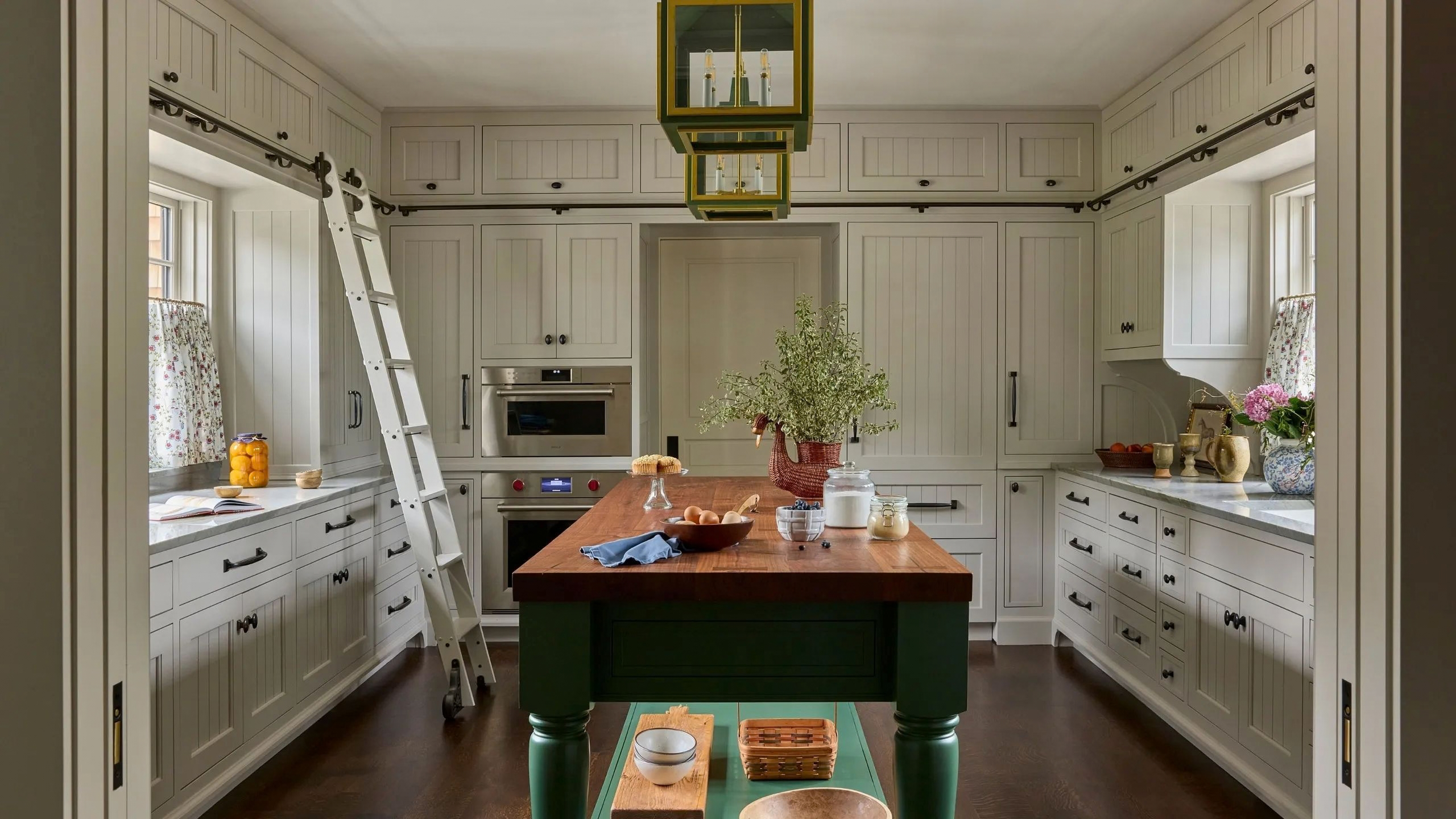 a large kitchen with lots of cabinetry, a central island, and a ladder around the perimeter