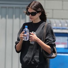 Kaia gerber wears a black sweatshirt, micro foldover shorts, and on running sneakers.