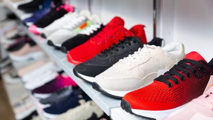 Store shelf with sports shoes lined up.