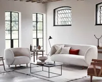 A white boucle sofa with a rounded cocoon shape in a modern living room with Crittall doors