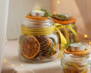 dry slices of citrus, cones, and spruce twigs in mason glass jars