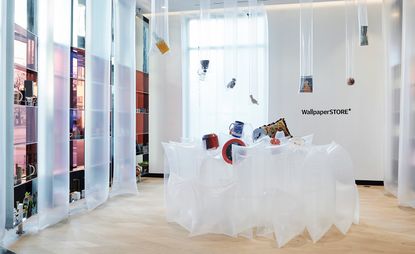 Inside a Wallpaper store pop-up with items hanging from the ceiling, some items inside clear plastic inflatable. The inflatables are also part of a feature in the middle of the room and around the room's perimeter. 