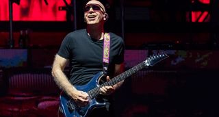 Joe Satriani wears shades and shreds his chrome boy Ibanez signature guitar onstage at the Best Of All Worlds Tour 2024.