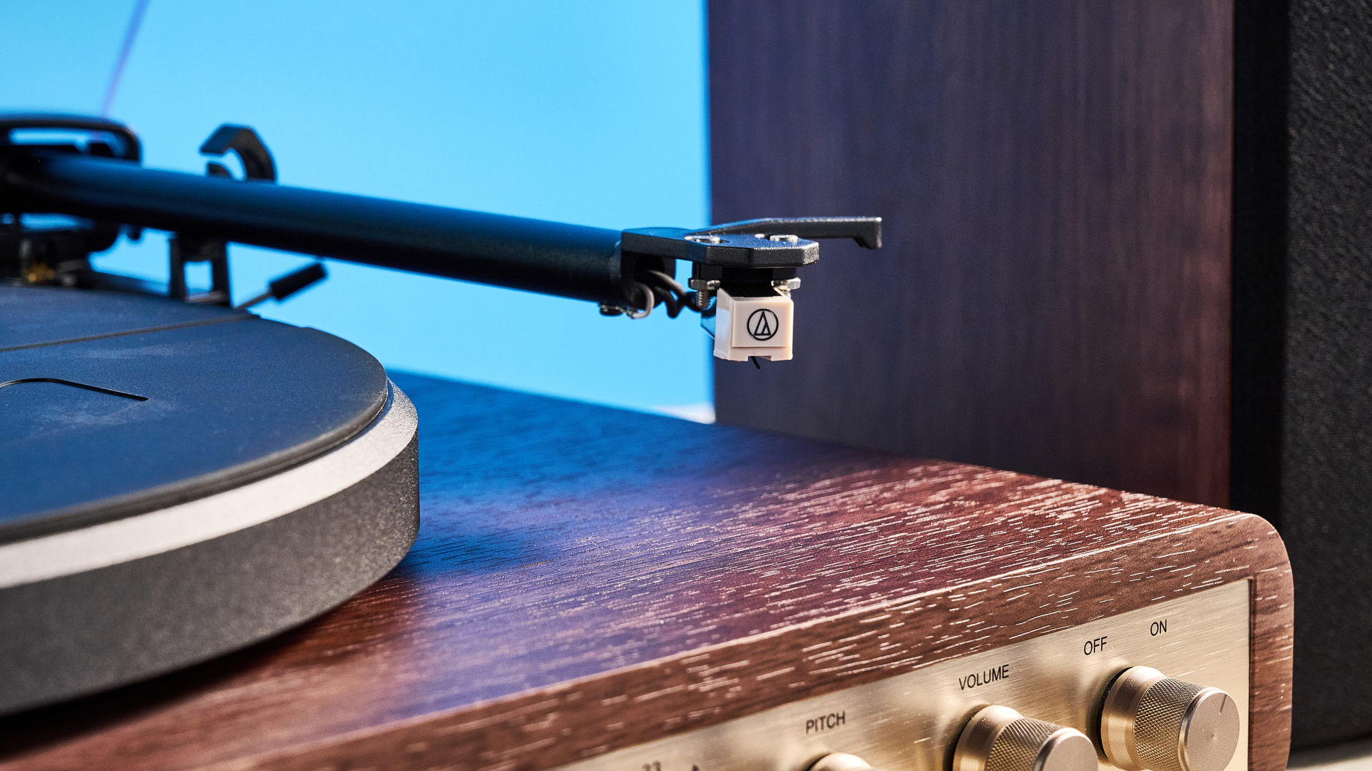Crosley C65 turntable and bookshelf speakers photographed in front of a blue background on a brown table.