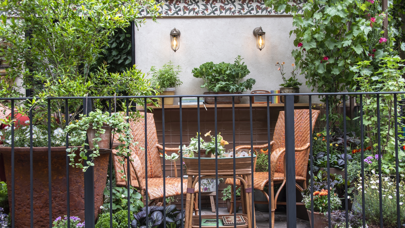 Two chairs and a table surrounded by shrubs and flowers in pots on a balcony at the RHS Chelsea Flower Show