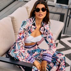 Model wearing clothing and sunglasses sold at Debenhams sat on a sofa
