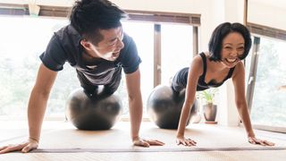 Man and woman doing decline press-up on gym balls
