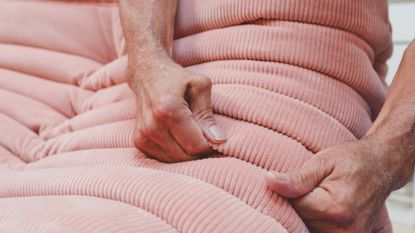 Close-up of a Ligne Roset upholsterer shaping and securing the soft pink folds of a Togo chair entirely by hand.