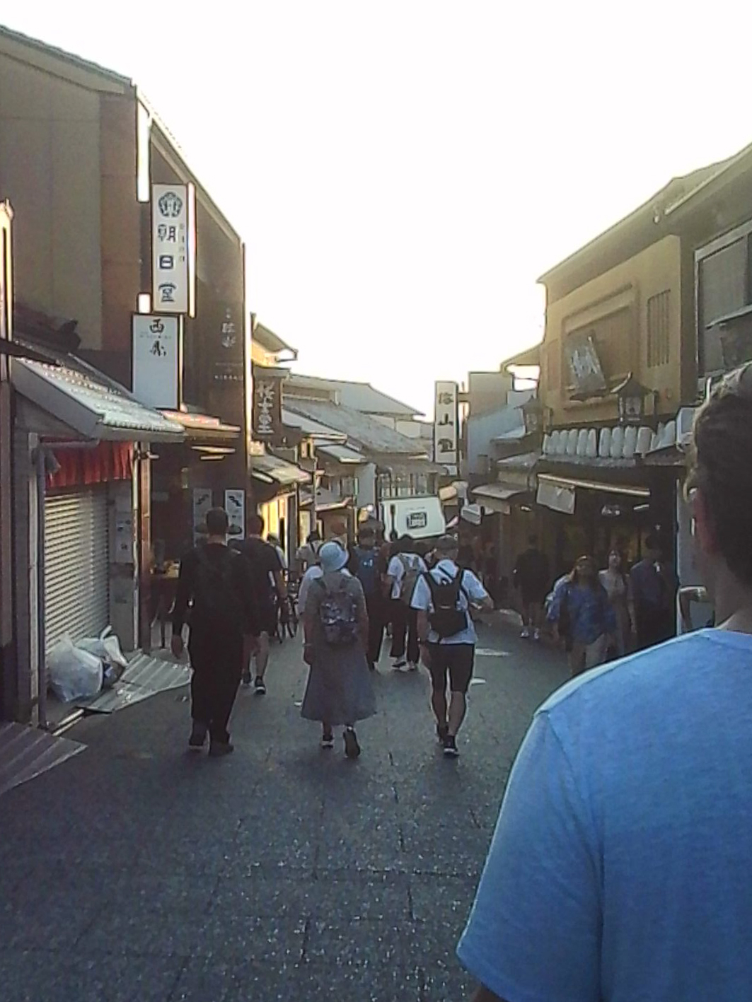Evening street in Japan with pedestrians walking past traditional storefronts.