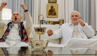 The Two Popes Jonathan Pryce and Anthony Hopkins watching TV on the couch