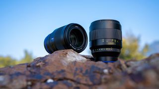 Zeiss Otus ML 50mm and 85mm F1.4 lenses together on a rock, blue skies