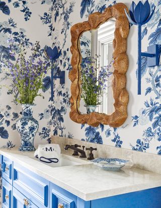 bathroom with blue and white wallpaper, gold mirror and blue vanity