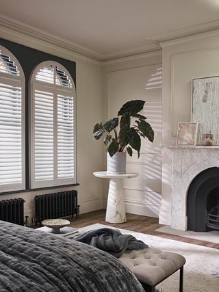 Bedroom within a Victorian property showing arched windows with white traditional shutters