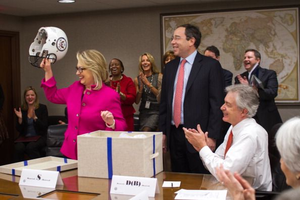 Hillary Clinton holds a football helmet gifted by Deputy Secretary Tom Nides in 2013.