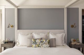 primary bedroom with grey walls and white fourposter bedframe and floral pillow