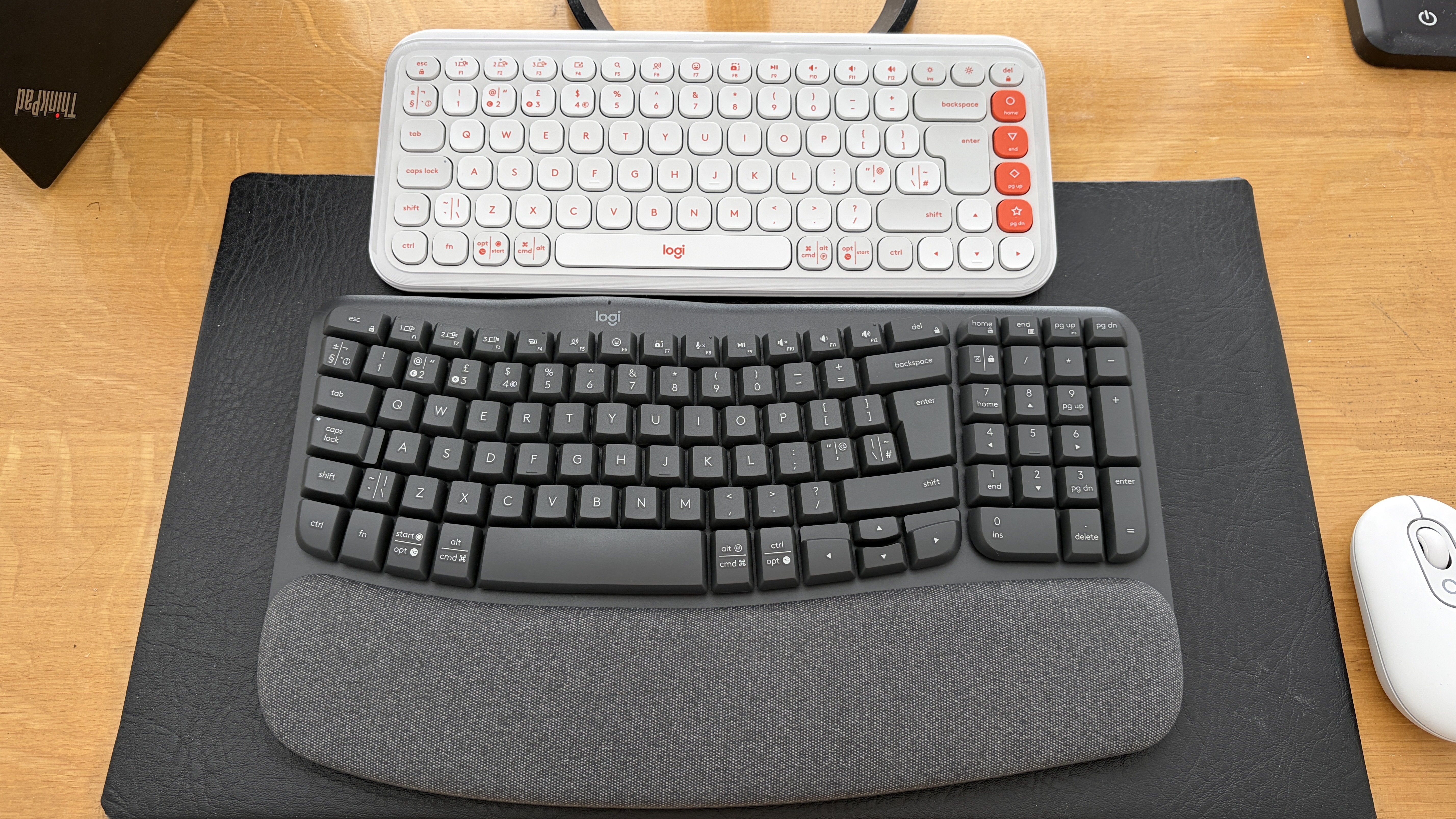 The Logitech Pop Icon Keys and Logitech Wave keys on a wooden table