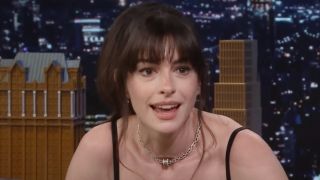 Anne Hathaway leaning forward and talking to the crowd on The Tonight Show.