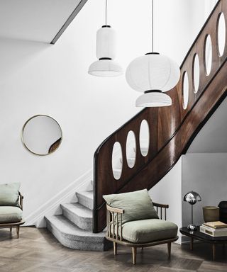 Brown statement stair railing idea by Nest with green chair in hallway and lantern lighting