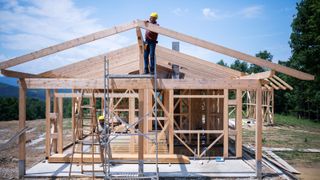 Construction Workers Working On Wooden Roof Of House