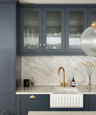 Dark grey kitchen cabinets with glass front, above marble backsplash in modern kitchen space