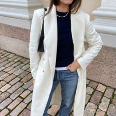 @johannapiispa wears a cream frock coat with blue jeans and a tennis necklace 
