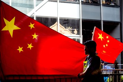Police officer stands in front of Chinese flag at pro-Beijing protest in Hong Kong.