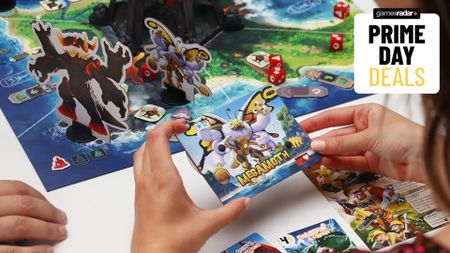 Someone holding a King of Monster Island card with the board and tokens nearby