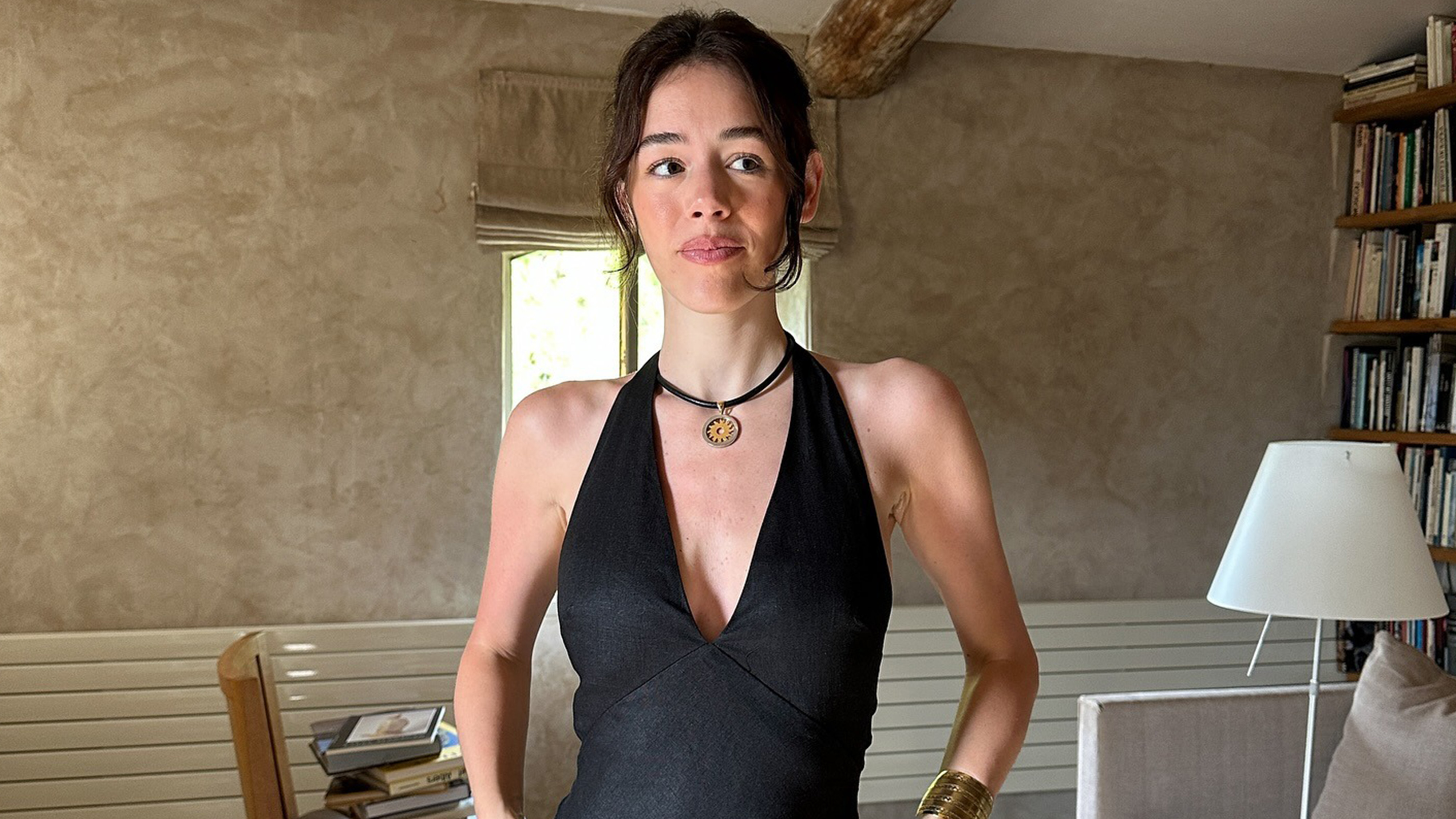 Ilana wears a necklace, black dress, and the row emi sandals.