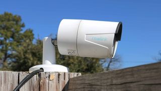 A Reolink PoE security camera on top of a fence