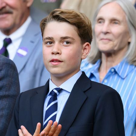 Prince George wears a navy suit with a striped tie and has floppy dark blonde hair