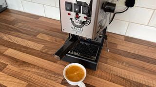 The Gaggia Classic on a kitchen countertop having just brewed an espresso